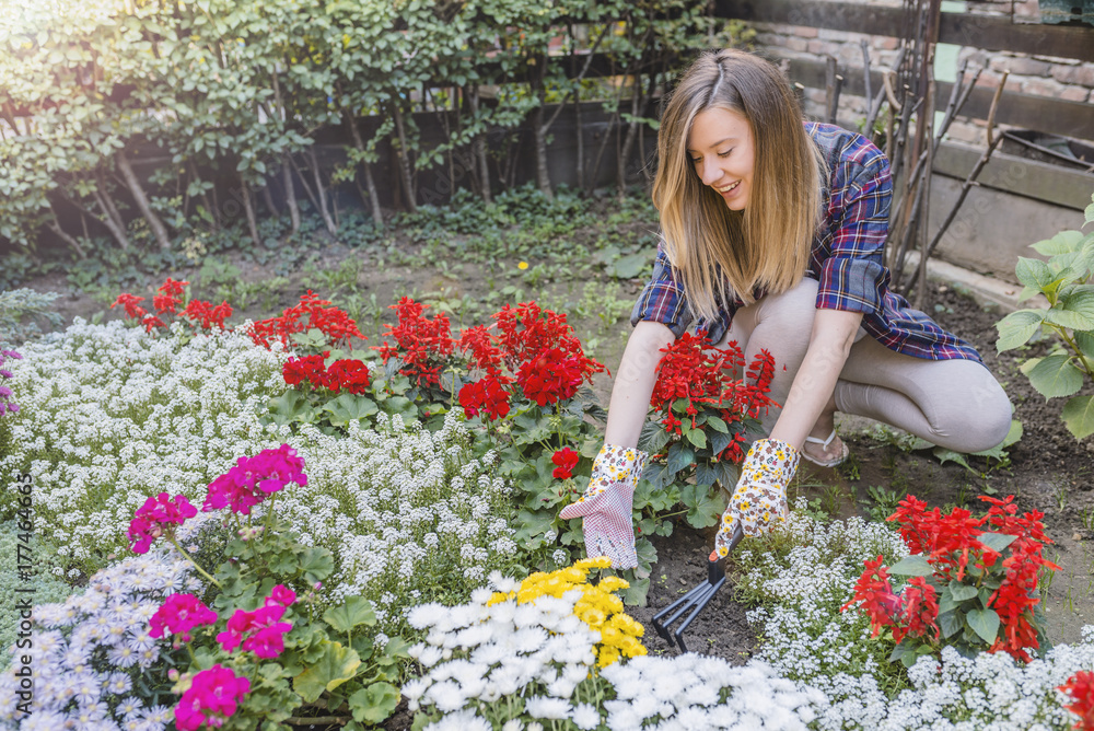 Smiling blond woman gardening. Young woman gardening outside and holding flowers