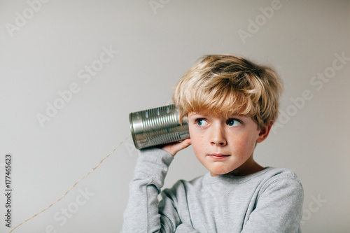 boy listening carefully to a tin can phone photo
