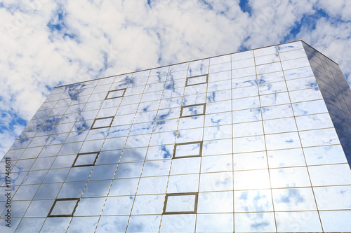Blue clouds and sun are reflected in the glasses of windows of a modern building. Right view