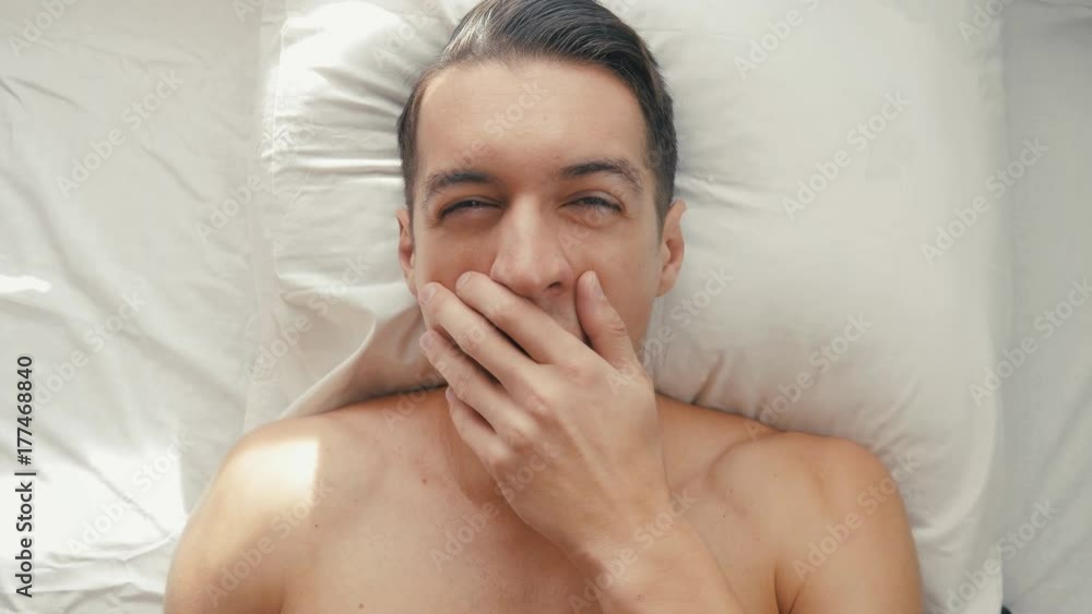Young man wakes up and yawns in the morning