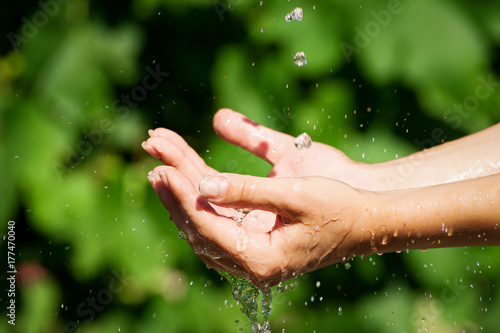 Woman washing hand outdoors. Natural drinking water in the palm. Hands with water splash, selective focus