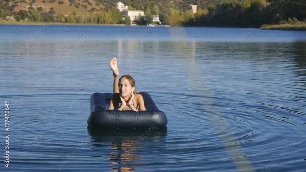 Young slim girl floats on inflatable mattress. Slow motion
