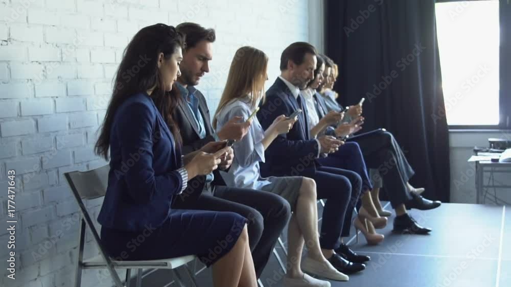 Group Of Business People Using Cell Smart Phones Typing Messages On Modern Gadgets Businesspeople Sitting In Row Slow Motion Group Of Business People Using Cell Smart Phones Typing Messages On Modern Gadgets Businesspeople Sitting In Row Slow Motion