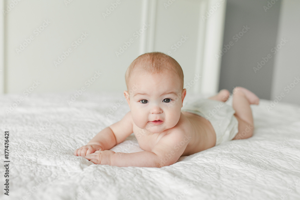 4 month old baby laying on tummy on white bed 4 month old baby laying on tummy on white bed
