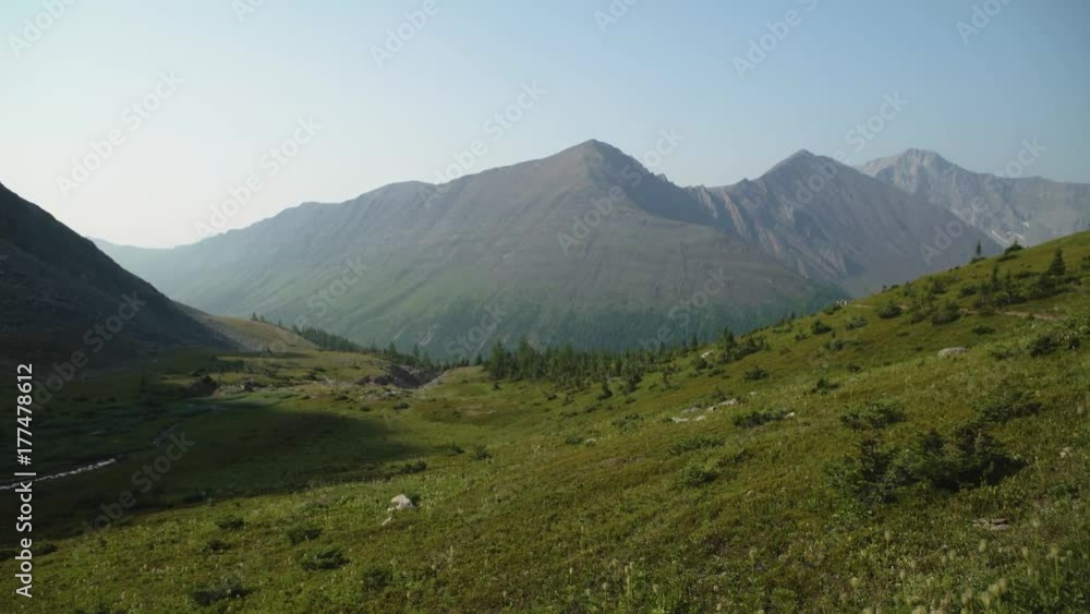 Wide shot panning around a clearing, looking at mountainous view, looking down at a forest