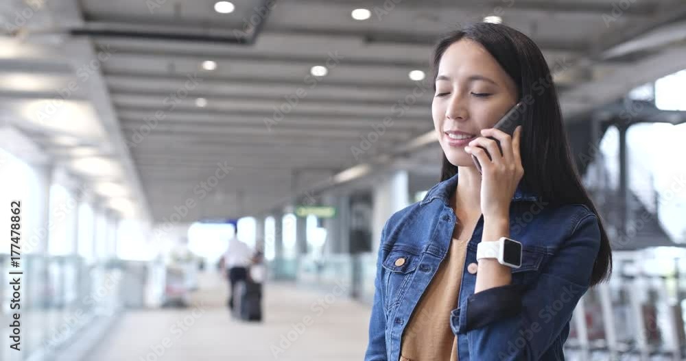 Woman talking on cellphone and checking the time on smart watch in Hong Kong airport Woman talking on cellphone and checking the time on smart watch in Hong Kong airport