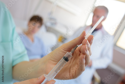 nurse removing sheath from hypodermic needle photo
