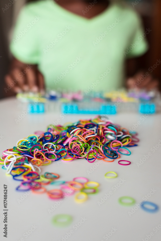 Young girl creating a bracelet  with a rubber bands