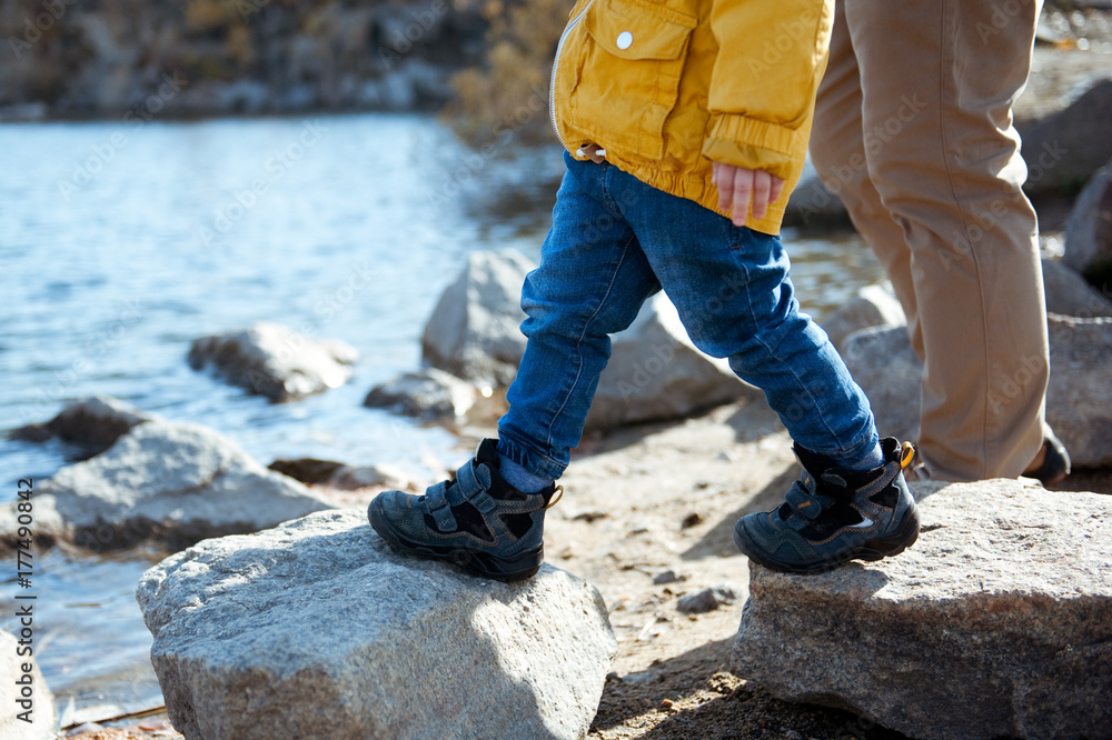 Father and son walking on the rocks near the lake.