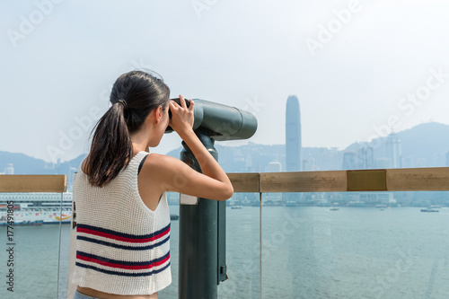 Woman looking though tourist binoculars in Hong Kong city