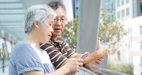 Senior retired couple using mobile phone at outdoor