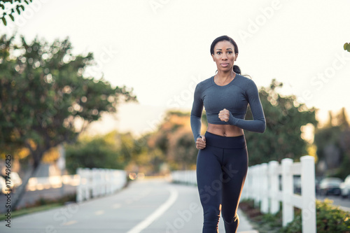 Beautiful dark skinned girl running on a path in a city park