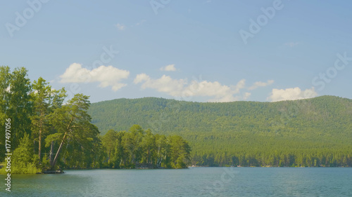 Beautiful blue clear water on the shore of the lake. Forest landscape at coast mirrored in water