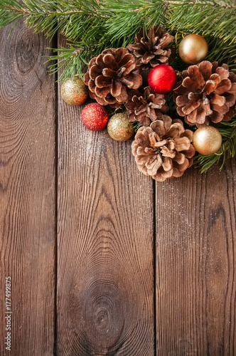 Christmas background. Fir tree branches, red and golden balls and cones on a wooden backdrop.