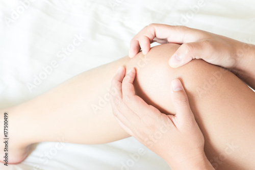 Closeup woman hand holding knee with pain on bed  health care and medical concept