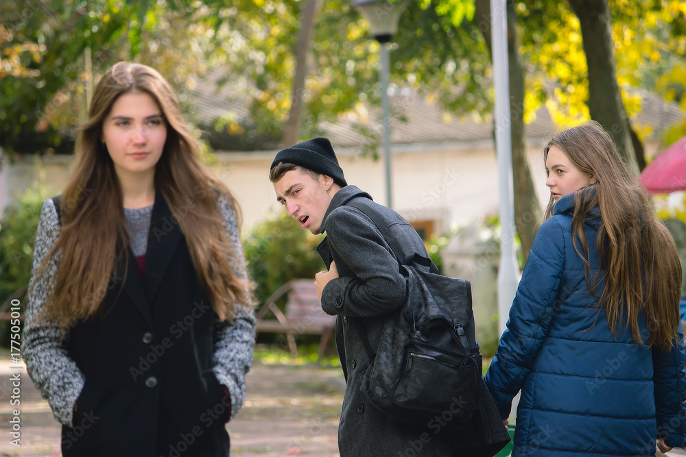 Disloyal man walking with girlfriend and looking amazed at another seductive girl Disloyal man walking with girlfriend and looking amazed at another seductive girl