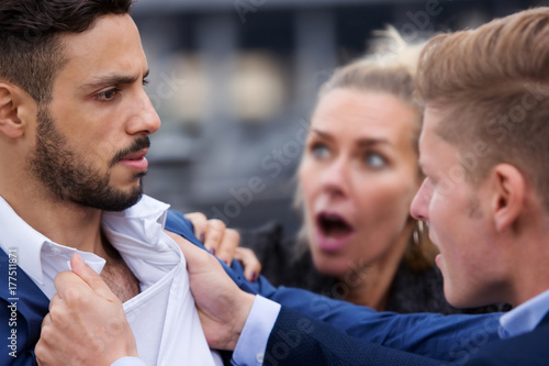 two men fighting while a woman is trying to intervene