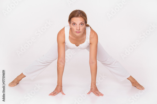 An adult woman doing yoga in a white hall. Beautiful woman doing stretching. © alatielin