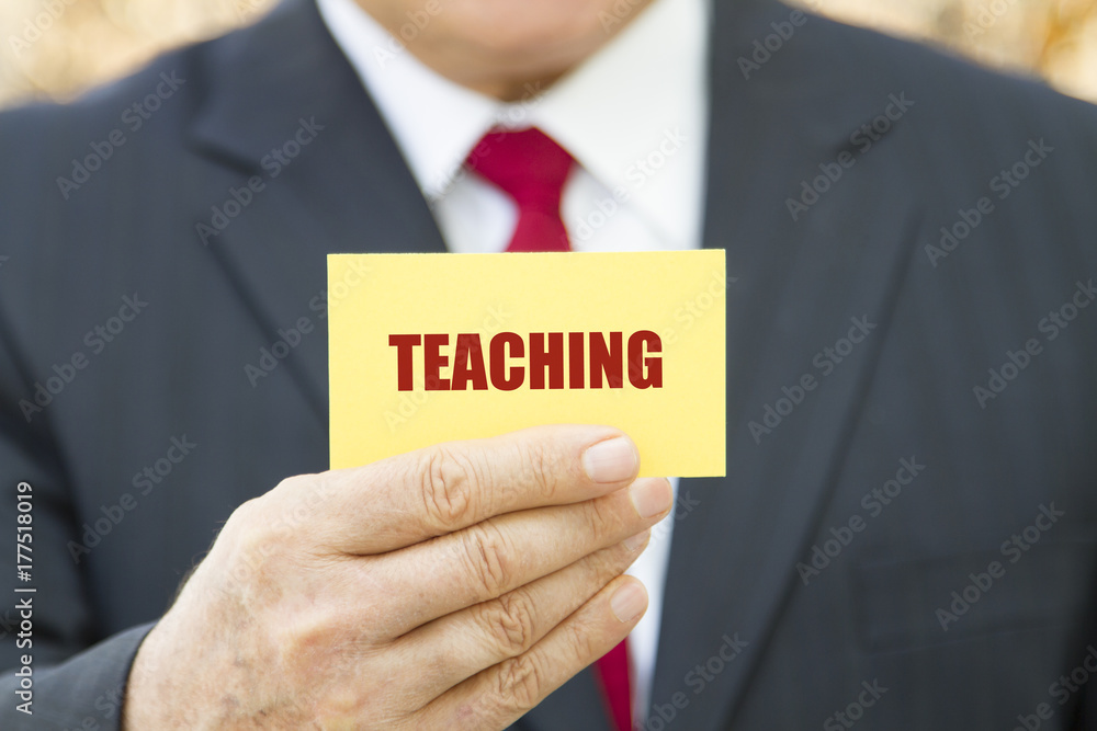 Businessman showing a card with text TEACHING Businessman showing a card with text TEACHING