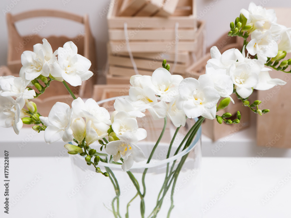 Close up beautiful bunch of white orchid in glass vase on table and wooden boxes background. Floristics workshop, floral arrangement for presents, tenderness in interior and decoration concept Close up beautiful bunch of white orchid in glass vase on table and wooden boxes background. Floristics workshop, floral arrangement for presents, tenderness in interior and decoration concept
