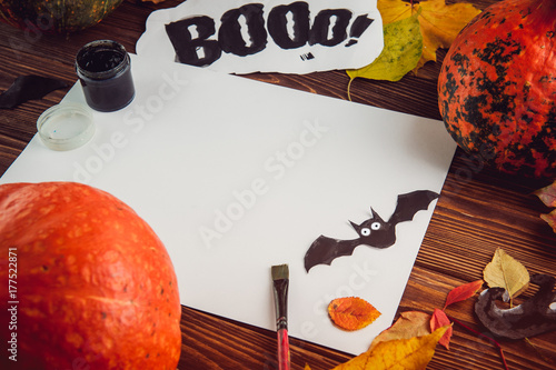 Halloween holiday background. Prepearing for party. Fresh pumpkins, coloured leaves, art, craft and painting materials on dark wooden table. Selective focus, top view. Space for text photo