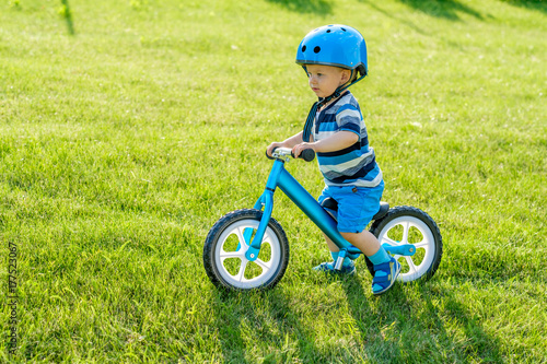 Boy in helmet riding a blue balance bike (run bike)