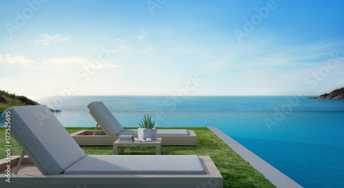 Sea view swimming pool beside terrace and beds in modern luxury beach house with blue sky background, Lounge chairs on green grass at vacation home or hotel - 3d illustration of tourist resort © terng99