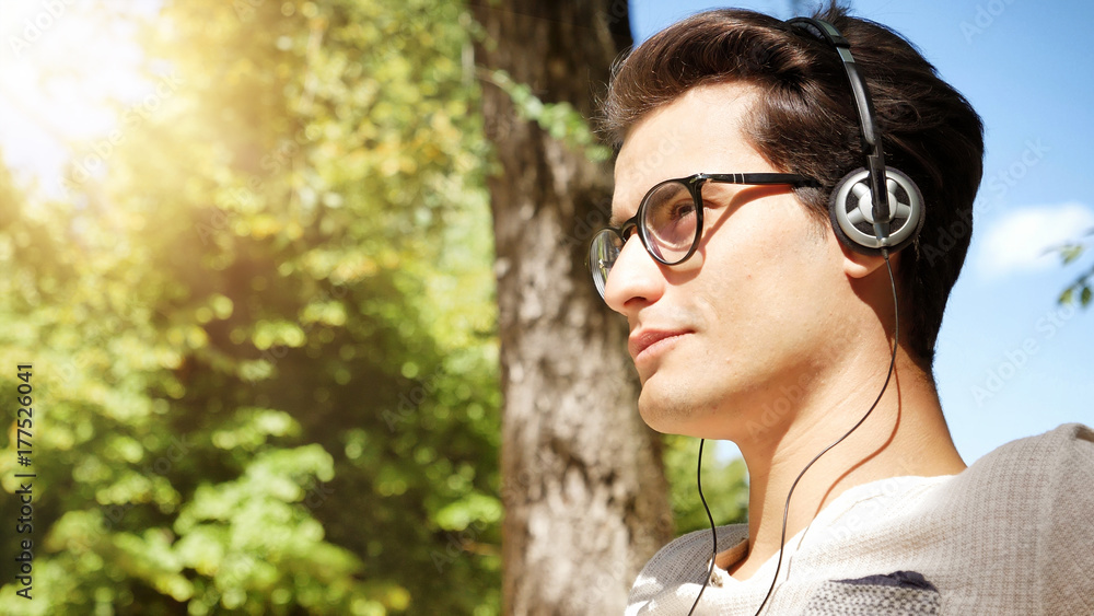 Close up Young Man Listening to his Favorite Music Using Headphone at the Park, Using MP3 Player