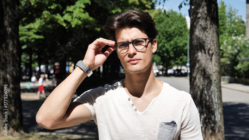 Stylish Young Handsome Man Standing in City Park, Looking at Camera