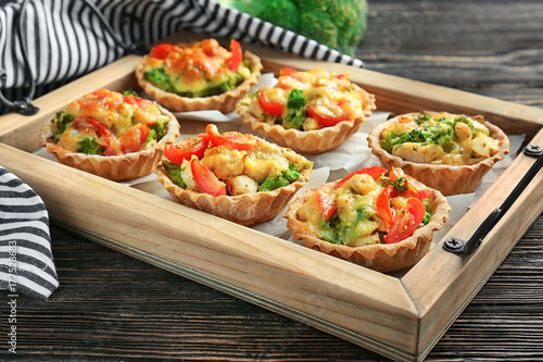 Delicious crispy tarts with broccoli on wooden tray