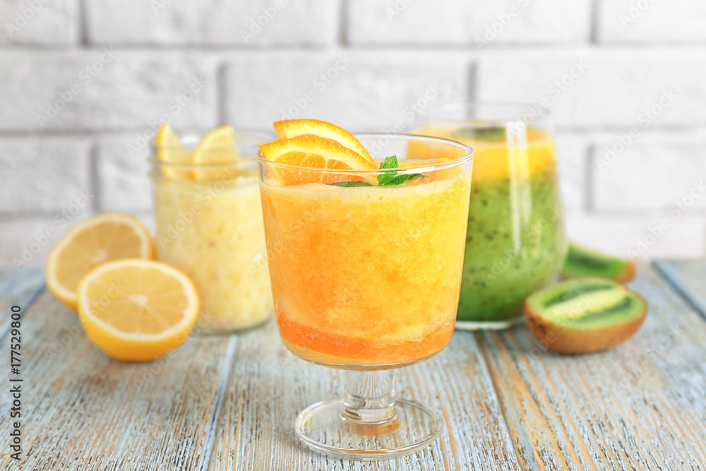Glasses with different smoothies on table against brick wall Glasses with different smoothies on table against brick wall