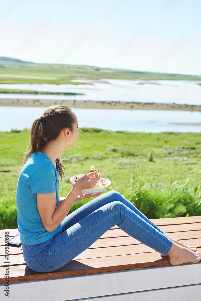young woman sitting outside the home and having breakfast on the terrace. Travel and vacation in Iceland young woman sitting outside the home and having breakfast on the terrace. Travel and vacation in Iceland