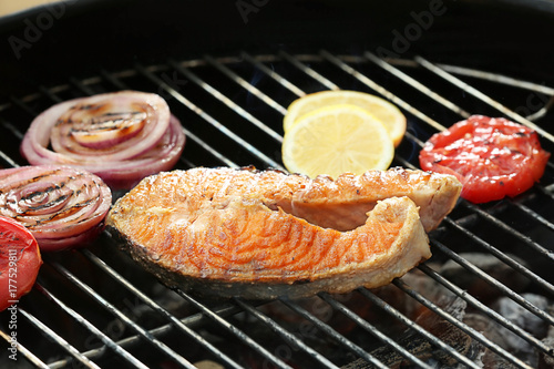 Tasty salmon steak with vegetables on barbecue grill, close up