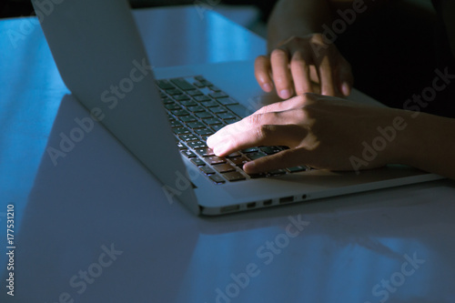 A computer programmer or hacker prints a code on a laptop keyboard to break into a secret organization system.