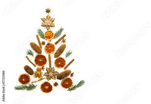 Christmas decoration. Twig christmas tree, christmas gingerbread, cones spruce, dried oranges, cinnamon sticks and stars anise on a white background with space for text. Top view, flat lay. photo