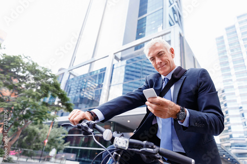 Successful businessman on bicycle with mobile phone