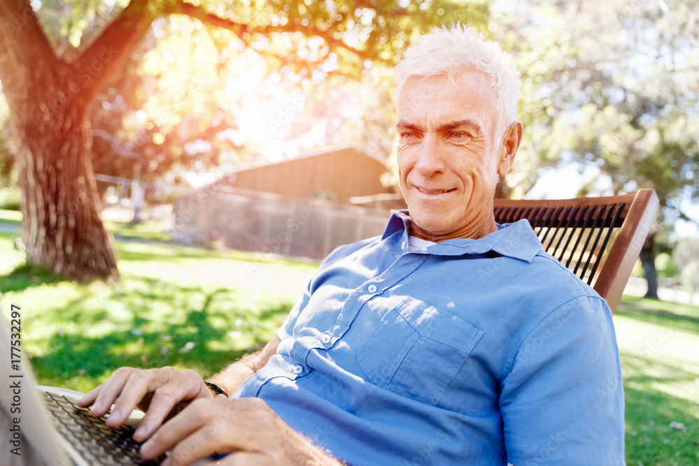 Senior man with notebook sitting in the park Senior man with notebook sitting in the park