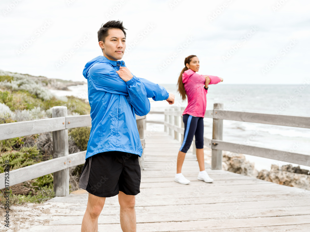 Fototapeta premium Young couple at the seaside doing exercises