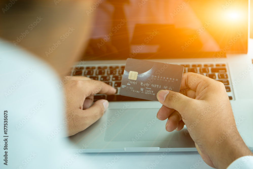 Hold a mobile credit card and use a laptop. Online shopping in the daytime