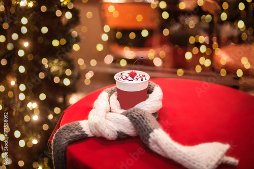 Coffee to go with wripped cream and cherry on a table covered with wool scarf, bokeh lights on background photo