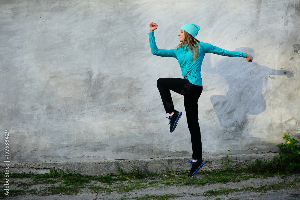 Sport step young woman, gray background, jumping sport outdoor, street, looking away, copy space