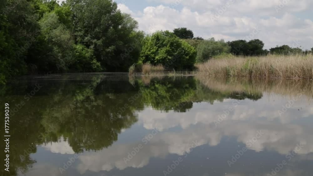 The boat glides over the lake, the sky is reflected on the surface The boat glides over the lake, the sky is reflected on the surface
