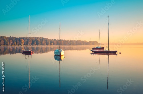 Beautiful autumn landscape. Red boat on the lake with colorful trees in the background. photo