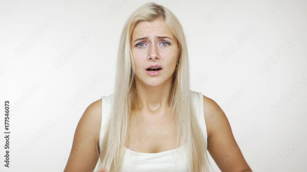 in slow motion angry young woman in white shirt wondering negatively saying no with annoyance over white background. Concept of emotions in slow motion angry young woman in white shirt wondering negatively saying no with annoyance over white background. Concept of emotions