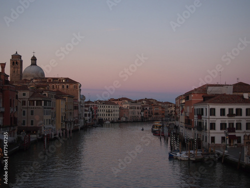 the grand canal in venice in evening twilight with sunset sky and street lights coming on with reflections or historic buildings and boats