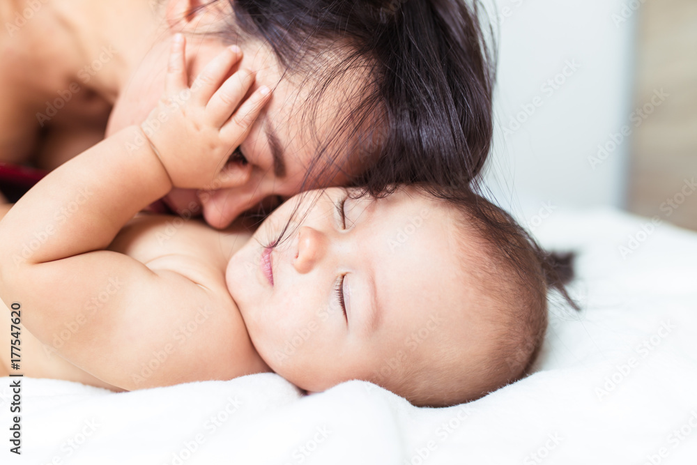 Beautiful mother enjoying and relaxing with her cute little baby on bed. Beautiful mother enjoying and relaxing with her cute little baby on bed.