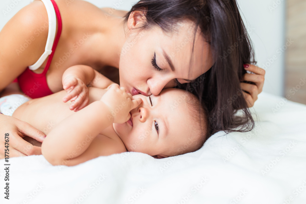 Beautiful mother enjoying and relaxing with her cute little baby on bed. Beautiful mother enjoying and relaxing with her cute little baby on bed.
