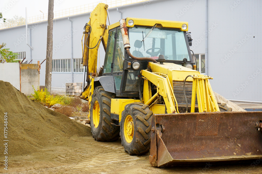 The concept of agronomy, a yellow tractor with a bucket demonstrates work The concept of agronomy, a yellow tractor with a bucket demonstrates work