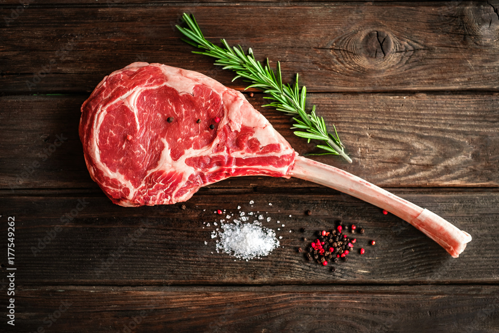 Fotografie, Obraz raw Tomahawk steak on wooden background with spices for  grilling | Posters.cz