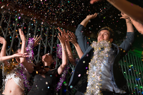 Young people dancing and showered with confetti on a club party on Friday night